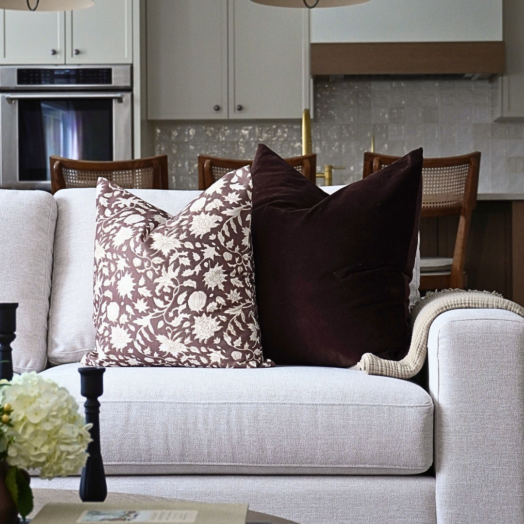 Gray sofa with patterned and solid brown pillows in a kitchen setting.