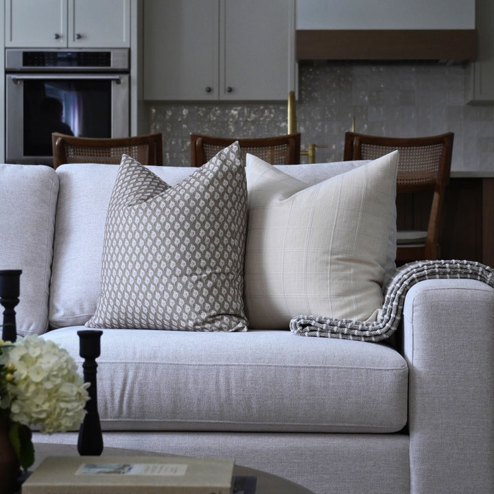 Gray sofa with patterned and plain pillows in a living room setting.