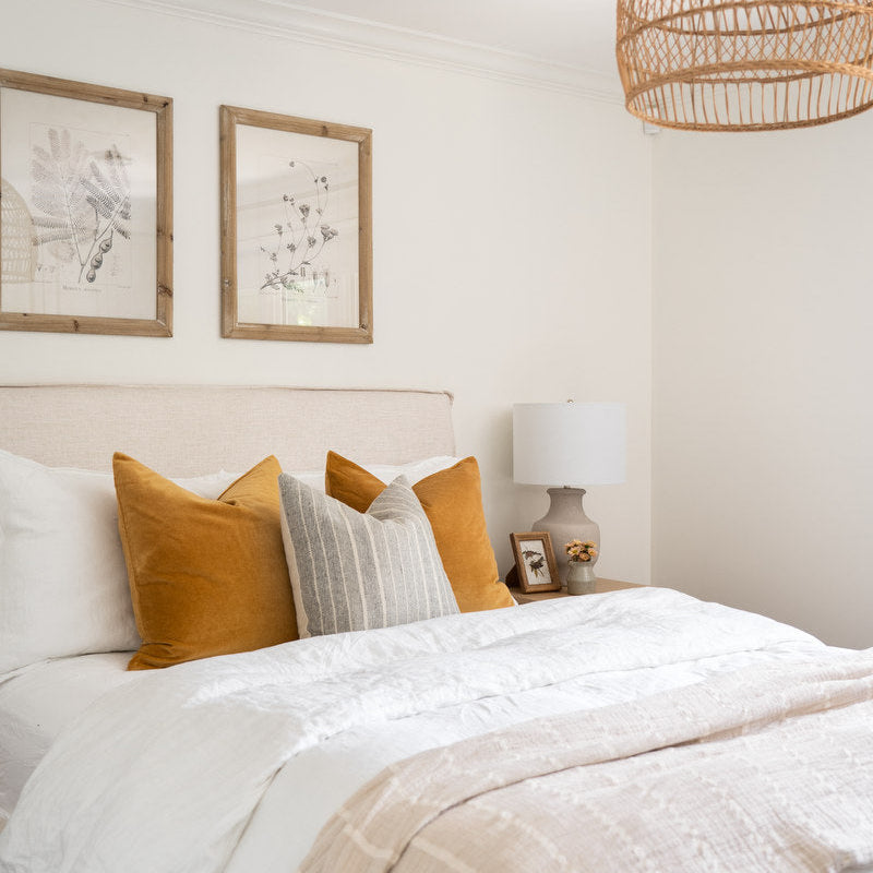 Neatly made bed with white bedding and yellow pillows in a bedroom setting.
